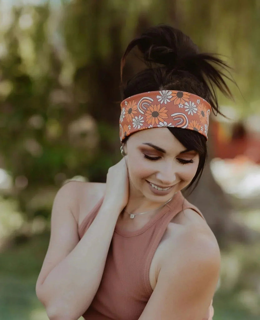 Smiling woman outdoors wearing orange floral workout headband and rust-colored tank top from Athena Fitness Collections