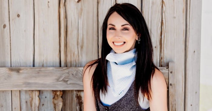 Woman wearing red paisley bandana neck scarf with Athena Fitness tag, smiling in natural light