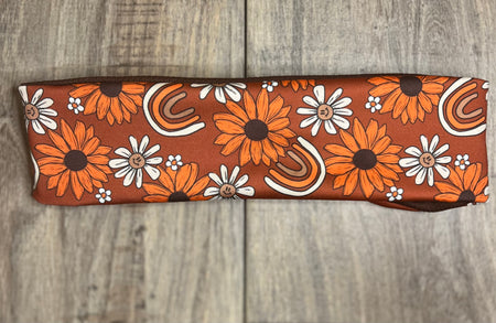 Brown background with brown and white smiley daisys and rainbows with brown moisture wicking underneath