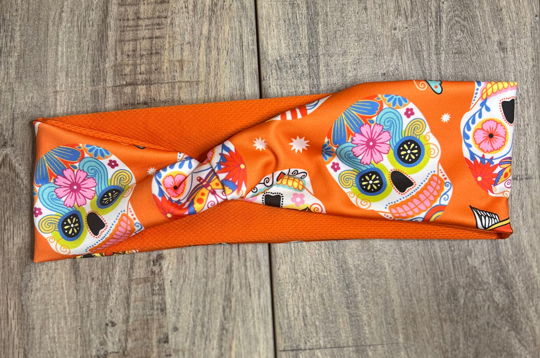 Sugar Skull with pink blue yellow and orange flowers on an orange background with moisture wicking underneath