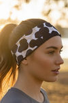 Woman wearing a patterned running headband with blue circles outdoors with a blurred natural background