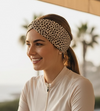 Woman with a bicycle on a balcony with palm trees in the background with cheetah headband on