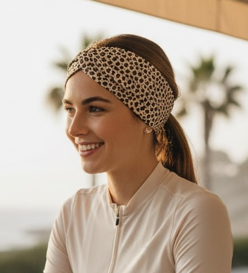 Woman with a bicycle on a balcony with palm trees in the background with cheetah headband on