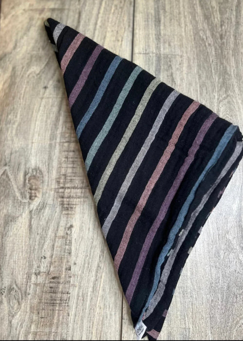 Folded black workout headband with muted multicolor stripes on wooden surface