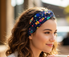 Woman holding a mug outdoors with a blurred background with an outer space headband