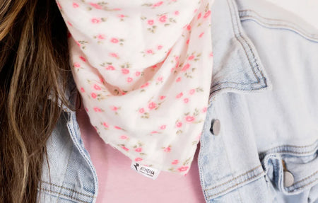 Person wearing a floral scarf and denim jacket with a visible brand label.