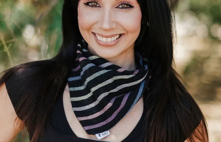 Smiling woman wearing a striped workout headband outdoors with green foliage background