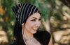 Smiling woman outdoors wearing a black headband with colorful stripes, inspired by Greek Isles