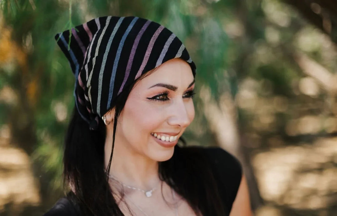 Smiling woman outdoors wearing a black headband with colorful stripes, inspired by Greek Isles