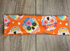 Sugar Skull with pink blue yellow and orange flowers on an orange background with moisture wicking underneath