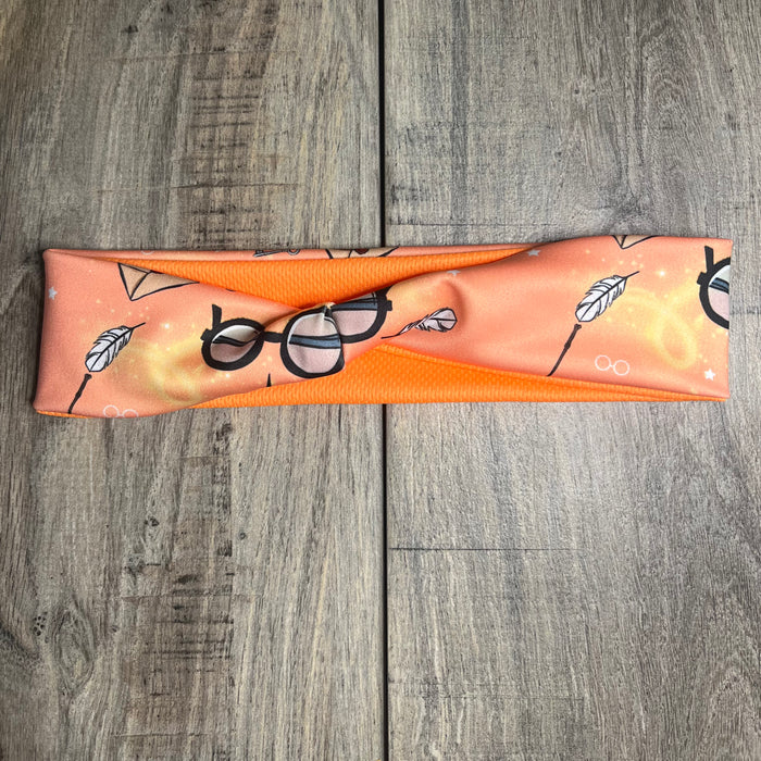 Orange background with white feathers and Wizard glasses with orange moisture wicking underneath to match