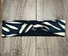 Handmade black and white patterned workout headband twisted at center on wood floor moisture wicking material underneath