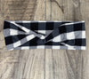 Black and white checkered workout headband with a twisted knot design on wood surface