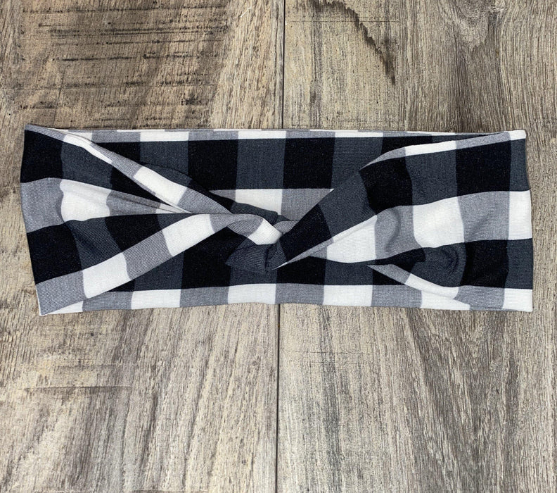 Black and white checkered workout headband with a twisted knot design on wood surface