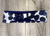 Handmade workout headband with navy blue and white polka dot design on wood background