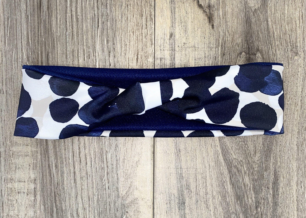 Handmade workout headband with navy blue and white polka dot design on wood background