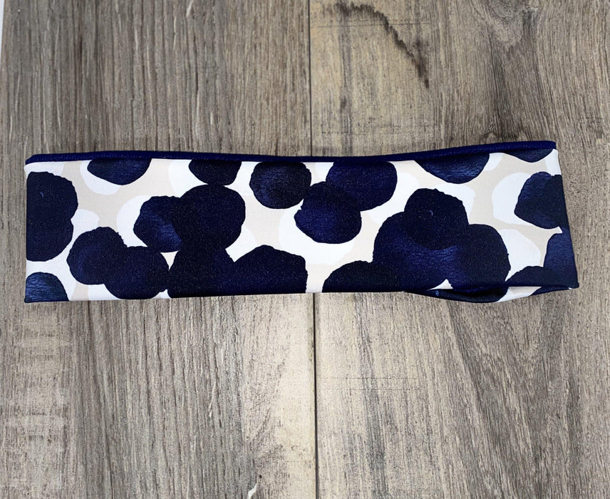Athena Fitness handmade workout headband with navy blue and white abstract pattern on wood background