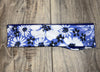 Handmade workout headband with white and black floral pattern on blue background, placed on wooden floor