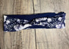 Navy and white handmade workout headband with floral and dot pattern on wooden surface