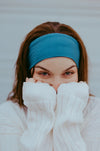 Woman wearing a blue workout headband and cozy white sweater covering her face, close-up