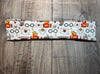 Athena Fitness Collections white workout headband with witch inspired print featuring glasses, letters, keys, scarves, and magical symbols on wood background