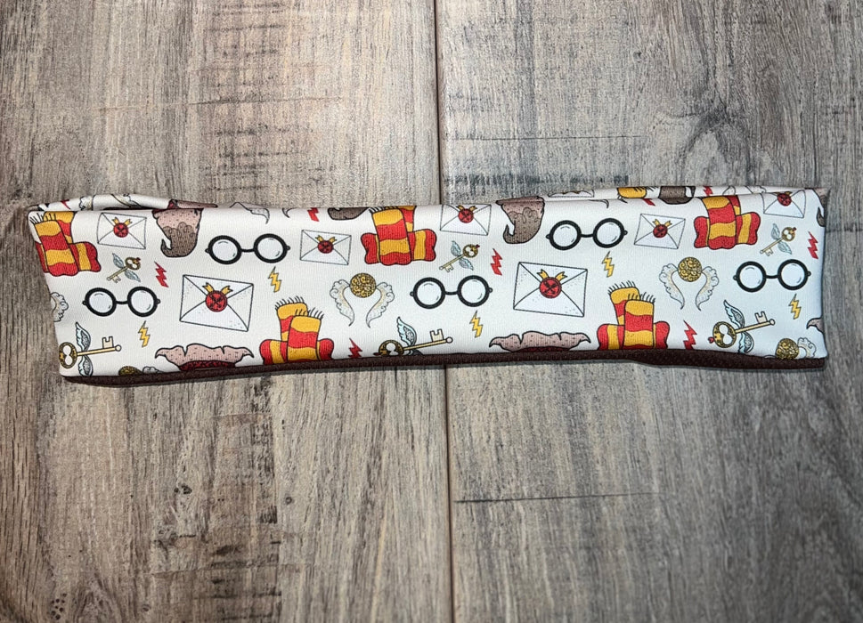 Handmade workout headband with wizard inspired glasses, scarf, key, and golden snitch design on wood background