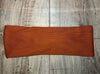 Copper-colored ribbed workout headband on light wood floor from Athena Fitness Collections