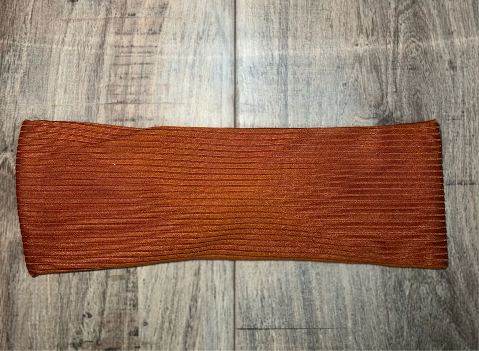 Copper-colored ribbed workout headband on light wood floor from Athena Fitness Collections