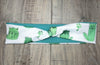 Athena Fitness handmade workout headband with green cactus cat prints and teal fabric on wooden background