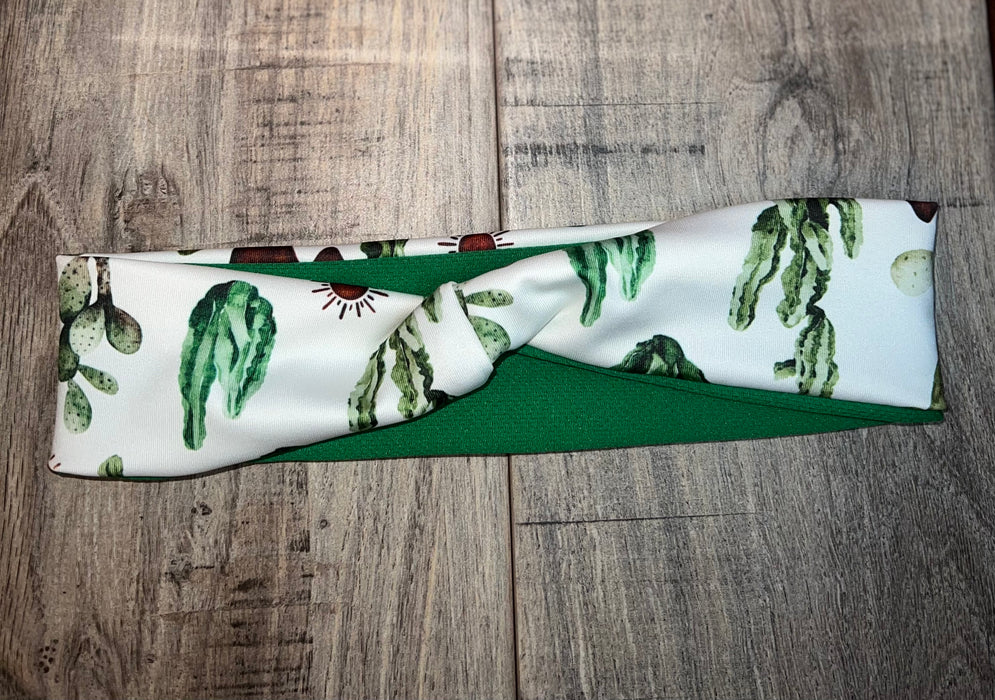 Handmade workout headband with green cactus print and solid green fabric on wooden surface