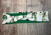 Handmade workout headband with cactus print pattern on white fabric and solid green back, laid flat on wooden surface