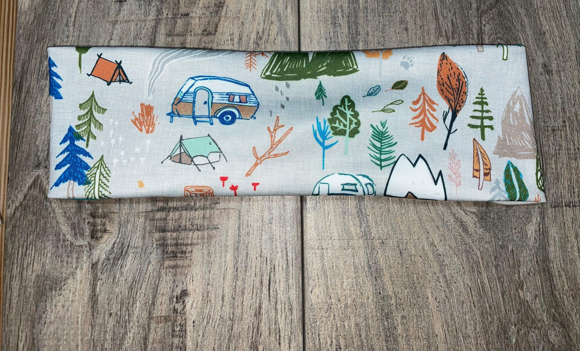 Athena Fitness handmade headband with colorful camping and nature-themed print on wooden surface
