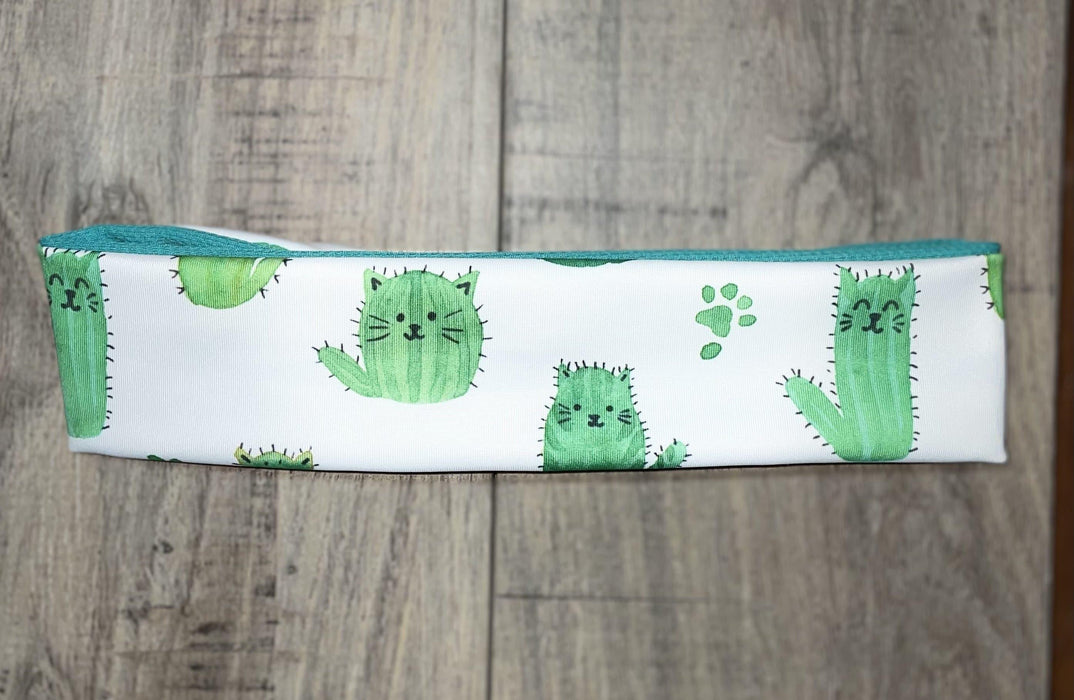 Handmade workout headband with cute green cactus-cat print on white fabric, teal inner lining