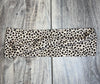 Leopard print handmade workout headband with twist design on wooden background