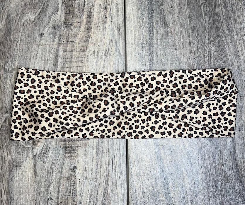 Leopard print handmade workout headband with twist design on wooden background