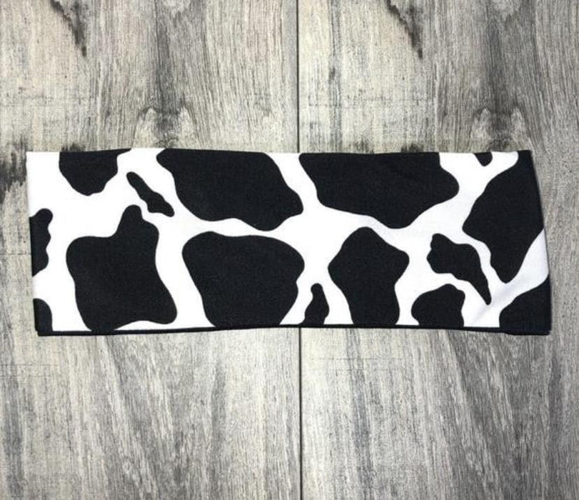 Black and white cow print workout headband laid flat on wooden floor background