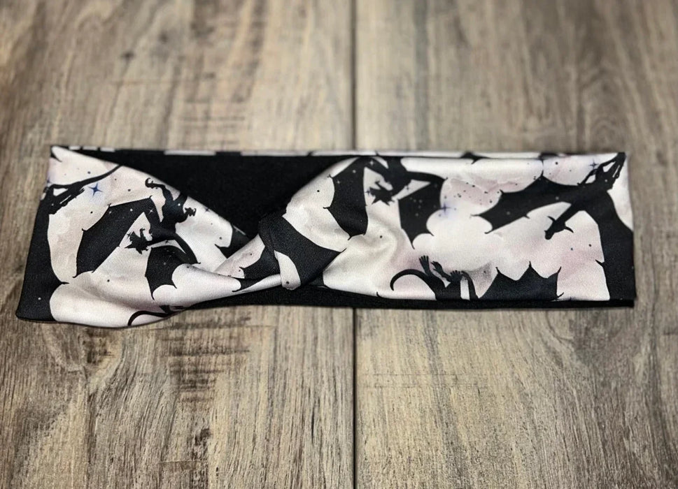 Athena Fitness handmade black and white workout headband with dragon wing pattern on wooden surface