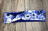 Blue workout headband with white floral print on wooden surface, handmade fitness accessory