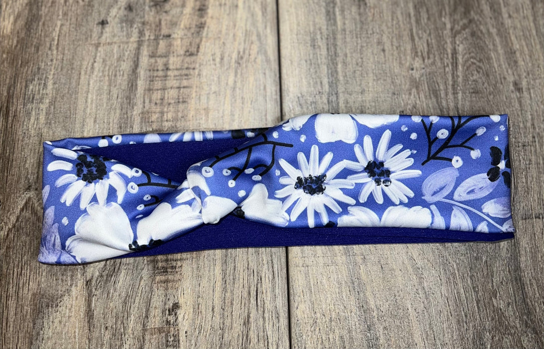 Blue workout headband with white floral print on wooden surface, handmade fitness accessory