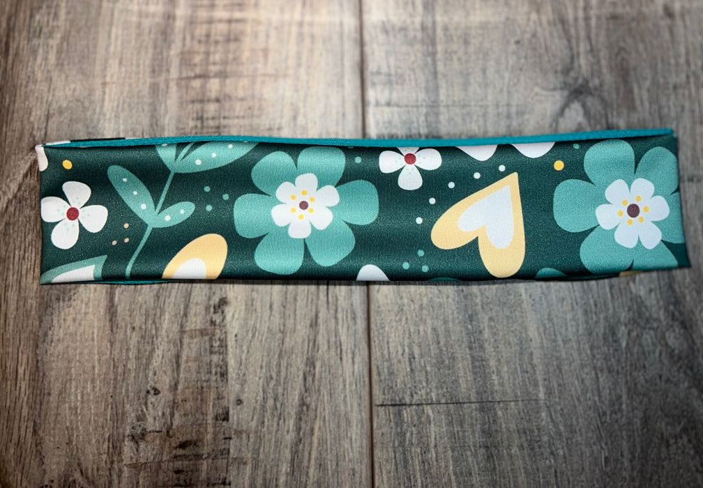 Handmade workout headband with green background, floral and heart patterns on wooden surface