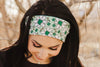 Woman outdoors wearing a green and white floral workout headband from Athena Fitness Collections with bare trees background