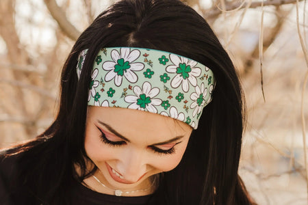 Woman outdoors wearing a green and white floral workout headband from Athena Fitness Collections with bare trees background