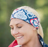 Smiling woman wearing a blue and white patterned workout headband and draped with an American flag outdoors