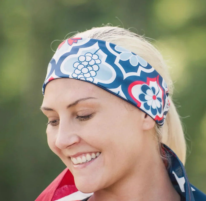 Smiling woman wearing a blue and white patterned workout headband and draped with an American flag outdoors