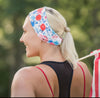 Woman in a floral handmade workout headband with blonde ponytail and black athletic top outdoors