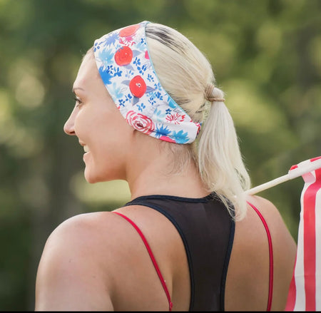 Woman in a floral handmade workout headband with blonde ponytail and black athletic top outdoors