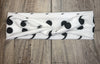 White workout headband with black semicolon pattern, knotted center on rustic wood background