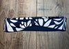 Navy blue and white handmade moisture wicking workout headband with leafy pattern on wooden surface