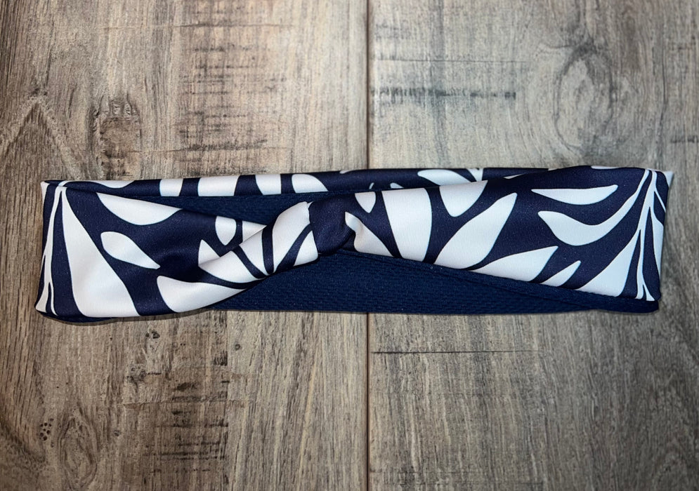 Navy blue and white handmade moisture wicking workout headband with leafy pattern on wooden surface
