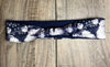 Navy blue workout headband with white floral pattern from Athena Fitness Collections on wooden surface